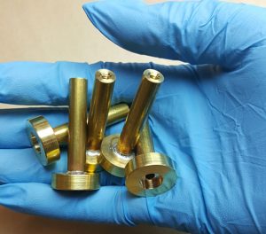 A gloved hand displaying parts in poor condition which can affect proper metal plating