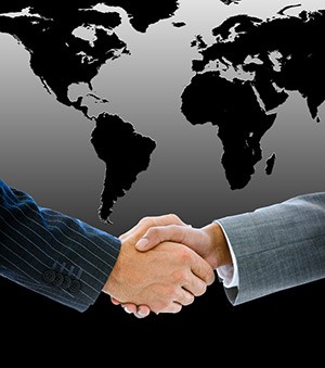Two businessmen shaking hands in front of a map of the world
